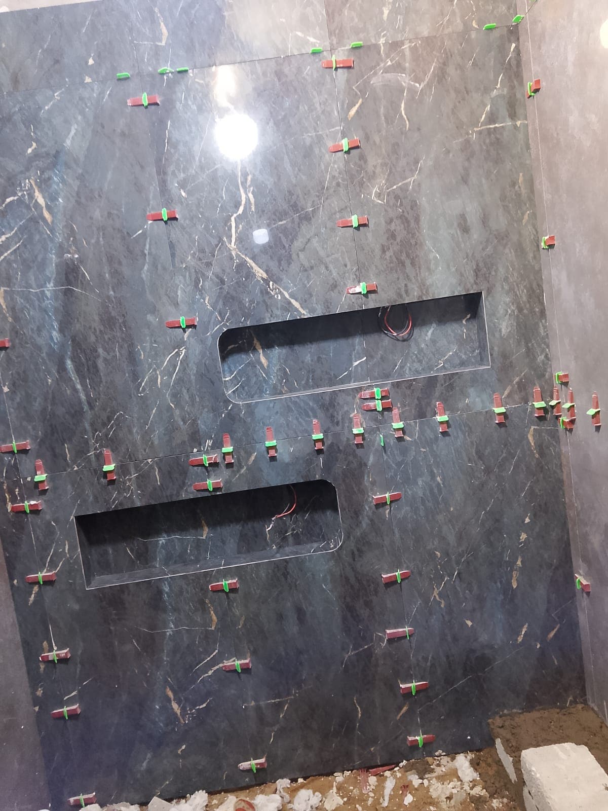 Dark vein-matched porcelain feature wall with two illuminated niches, Islamabad